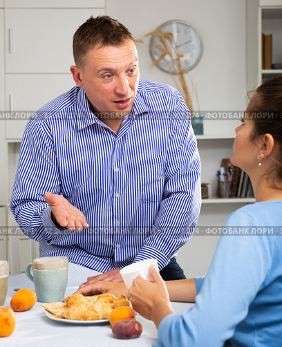 Upset man and frustrated woman arguing at home kitchen. Focus on woman. Стоковое фото, фотограф Яков Филимонов / Фотобанк Лори