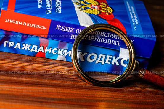 Увеличительное стекло и Кодексы Российской Федерации Гражданский и об административных правонарушениях лежат на столе (2023 год). Редакционное фото, фотограф Николай Винокуров / Фотобанк Лори