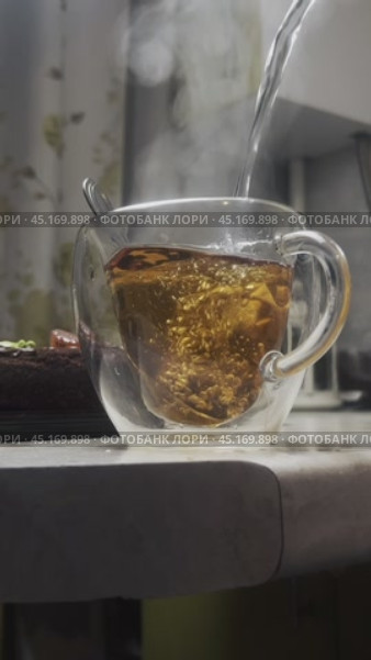 В прозрачную чашку с чайным пакетиком наливается кипяток. Заваривается свежий чай.  Заготовка для reels. Стоковое видео, видеограф Ярославский Максим / Фотобанк Лори