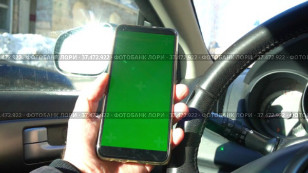 В руке водителя за рулем машины смартфон с зеленым экраном. За окном проезжает автомобиль. Замедленная съемка с движением камеры вправо. Стоковое видео, видеограф Sergei Gorin / Фотобанк Лори
