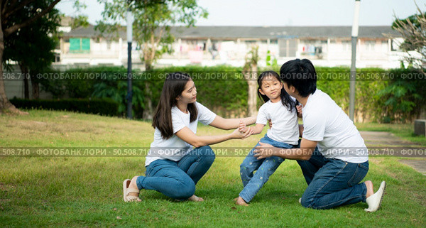 Vacation for a young family Spend this priceless time together playing on the village lawn. A little girl was slightly injured while playing with her parents comforting her at her side. Стоковое фото, агентство Ingram Publishing / Фотобанк Лори