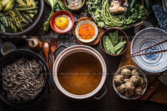 Various asian food ingredients for tasty soba noodles soup around cooking pot with delicious miso broth or stock on rustic kitchen table background, top view. Asian cuisine background. Healthy eating. Стоковое фото, агентство Ingram Publishing / Фотобанк Лори