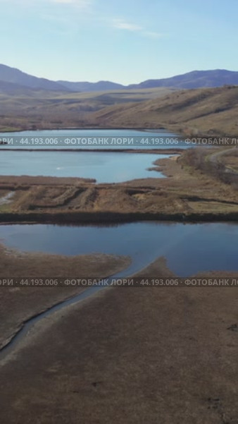 Vertical drone video of flying over a hilly rural landscape with a winding road and fish ponds. Altai Krai. Стоковое видео, видеограф Сергей Пристяжнюк (Serg Zastavkin) / Фотобанк Лори