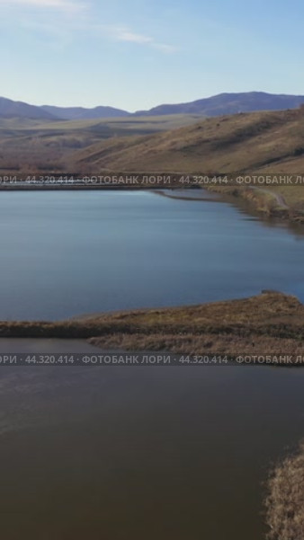 Vertical drone video of flying over a hilly rural landscape with a winding road and fish ponds. Altai Krai. Стоковое видео, видеограф Сергей Пристяжнюк (Serg Zastavkin) / Фотобанк Лори