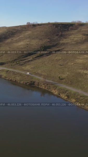 Vertical drone video of flying over a hilly rural landscape with a winding road and fish ponds. Altai Krai. Стоковое видео, видеограф Сергей Пристяжнюк (Serg Zastavkin) / Фотобанк Лори