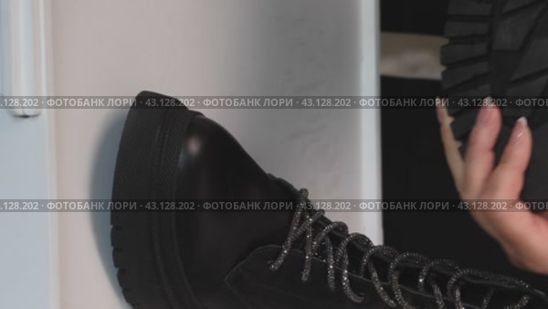 Vertical footage of a woman unveiling a new purchase - a pair of fashionable black lace-up boots. Watch as she gives a thorough review of the stylish footwear, perfect for fashion and lifestyle content. Стоковое видео, видеограф Vadzim Yakubovich / Фотобанк Лори