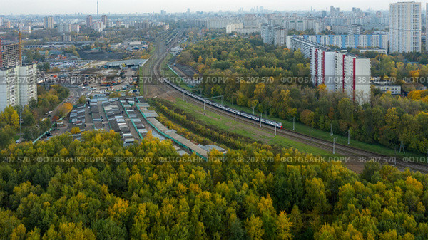 Вид с воздуха на жилые дома в московском районе Лианозово и Бескудниково со стороны Линозовского парка летним вечером на закате. Железнодорожная линия разделяет районы города (2021 год). Стоковое фото, фотограф Pukhov K / Фотобанк Лори
