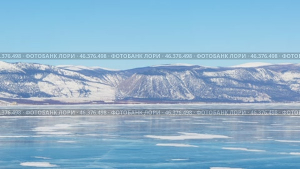 Video od winter Baikal Lake. Panoramic view of frozen Small Sea with beautiful blue clear ice surface and mountain range on sunny frosty February day. Natural background. Scenic landscape. Стоковое видео, видеограф Виктория Катьянова / Фотобанк Лори