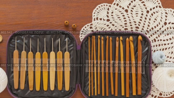 Video of accessories for crochet and handicrafts - set of crochet hooks in case, balls of light cotton yarn for crocheting and beautiful lace handmade napkins on wooden background. Flat lay, close-up. Стоковое видео, видеограф Виктория Катьянова / Фотобанк Лори