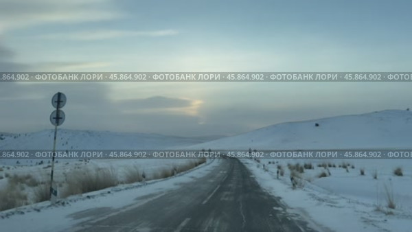 Video of winter snowy road on Tazheran steppe with snow-covered hills at sunset. Road to Baikal Lake coast. Scenic winter landscape. Natural background. Winter car traveling and outdoors. Стоковое видео, видеограф Виктория Катьянова / Фотобанк Лори