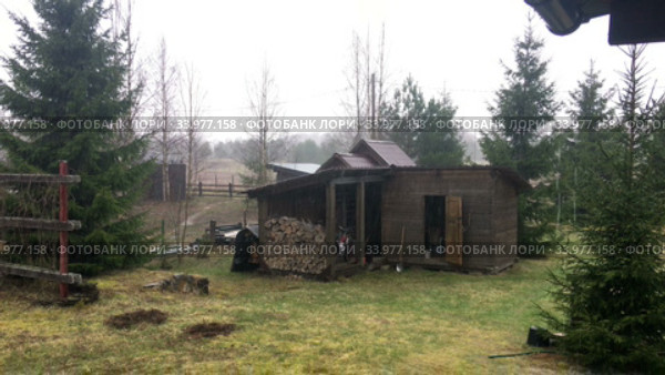 View at rainy and cloudy weather with rain falling in rural house backyard, wooden barn with meadow, spring season. Стоковое видео, видеограф Кекяляйнен Андрей / Фотобанк Лори