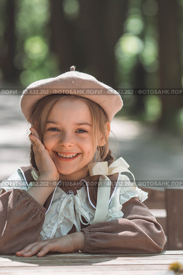 Vintage women's accessories and retro-style clothing. A small, beautiful girl with bows in her hair, in a beige dress and a beret outdoors. Стоковое фото, фотограф Photojuli / Фотобанк Лори