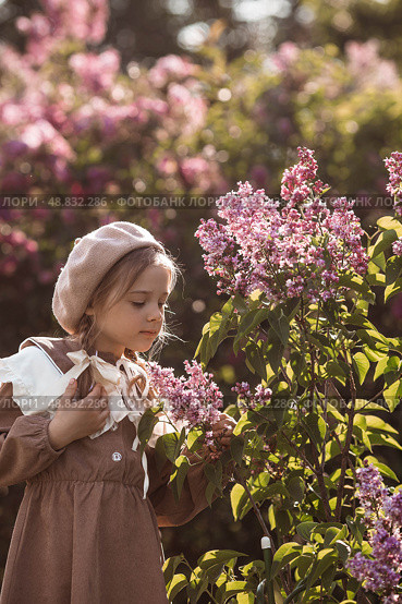 Vintage women's accessories and retro-style clothing. A small, beautiful girl with bows in her hair, in a beige dress and a beret outdoors. Стоковое фото, фотограф Photojuli / Фотобанк Лори