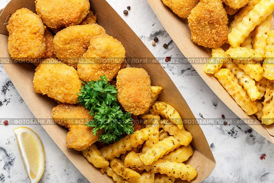 Вкусные наггетсы и картофель фри в бумажной коробке на светлом фоне. Стоковое фото, фотограф Pixel_shot / Фотобанк Лори