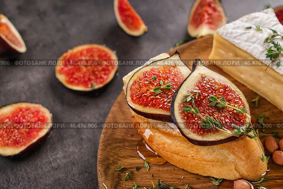 Вкусный бутерброд со спелым инжиром и сыром бри на деревянной тарелке, крупным планом. Стоковое фото, фотограф Pixel_shot / Фотобанк Лори