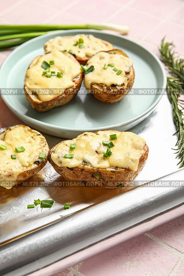 Вкусный запеченный картофель с сыром и рулетом из алюминиевой фольги на фоне цветной плитки, крупным планом. Стоковое фото, фотограф Pixel_shot / Фотобанк Лори