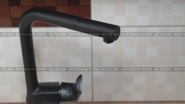 Водопроводная вода капает из стильного черного крана на кухне. Крупный план. Оригинальный звук. Стоковое видео, видеограф Sergei Gorin / Фотобанк Лори