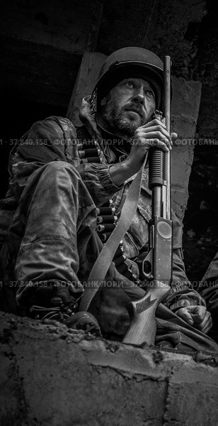 Вооружённый солдат, чёрно-белое фото. Воин в каске и  помповым ружьём. (2021 год). Редакционное фото, фотограф Виталий Михайлюк / Фотобанк Лори
