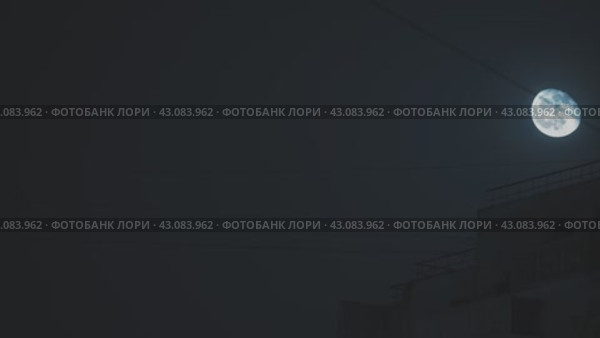 Восход луны над силуэтом здания. Массивный вид на луну, освещающую здание. Драматическая ночная сцена. Электрические кабели тянутся от здания. Замедленная съемка луны над городом. Стоковое видео, видеограф Воловодов Владимир / Фотобанк Лори