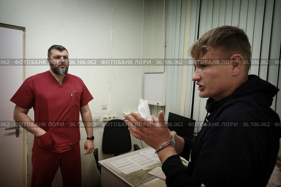 Врач освидетельствует задержанного полицейскими в травматологической поликлинике Балашихи (2021 год). Редакционное фото, фотограф Дмитрий Неумоин / Фотобанк Лори