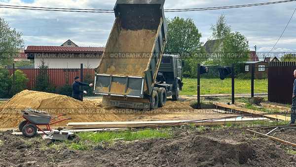 Выгрузка песка самосвалом на строительной площадке частного дома. Редакционное фото, фотограф Антон Моргунов / Фотобанк Лори