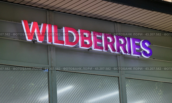 Вывеска компании Wildberries крупным планом. Световая подсветка логотипа. Точка доставки интернет-магазина. Russia (2024 год). Редакционное фото, фотограф Grigory_Gez / Фотобанк Лори