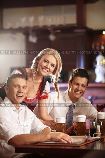Waitress in a German national costume next to a pub visitors. Стоковое фото, агентство Ingram Publishing / Фотобанк Лори