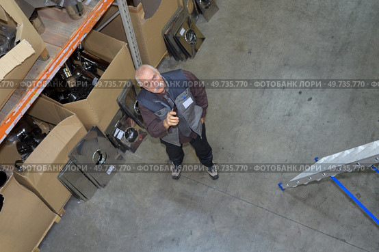 Warehouse worker looking up into racking. Стоковое фото, агентство Ingram Publishing / Фотобанк Лори