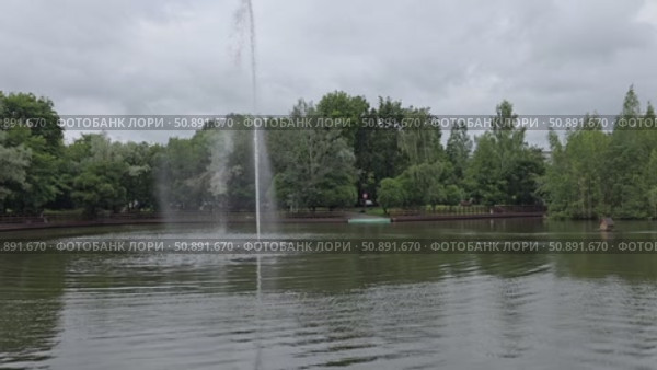 Water fountain spraying in calm lake surrounded by trees. Стоковое видео, видеограф Юрий Поздников / Фотобанк Лори