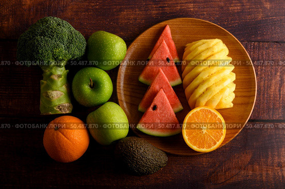 Watermelon, pineapple, oranges, cut into pieces with avocado, Broccoli and apples on wood table. Top view. Стоковое фото, агентство Ingram Publishing / Фотобанк Лори