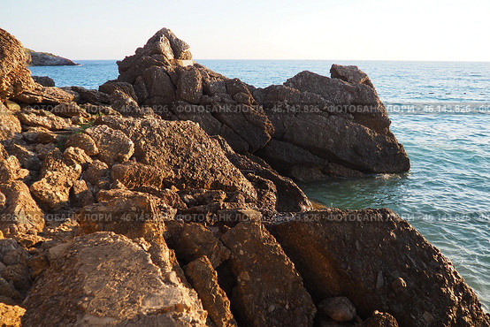 Waves gently crash against the rugged rocks while the sun sets over the horizon. Experience the serene beauty of this coastal location filled with natural wonders. Canj, Montenegro, Adriatic sea (2024 год). Стоковое фото, фотограф Юлия Петровская / Фотобанк Лори