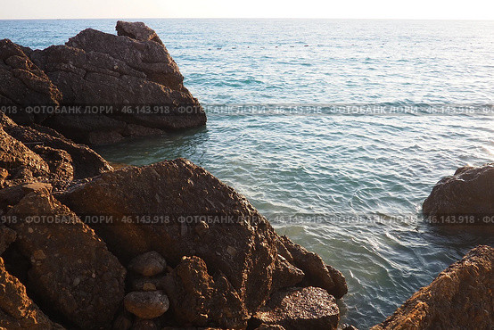 Waves gently crash against the rugged rocks while the sun sets over the horizon. Experience the serene beauty of this coastal location filled with natural wonders. Canj, Montenegro, Adriatic sea (2024 год). Стоковое фото, фотограф Юлия Петровская / Фотобанк Лори