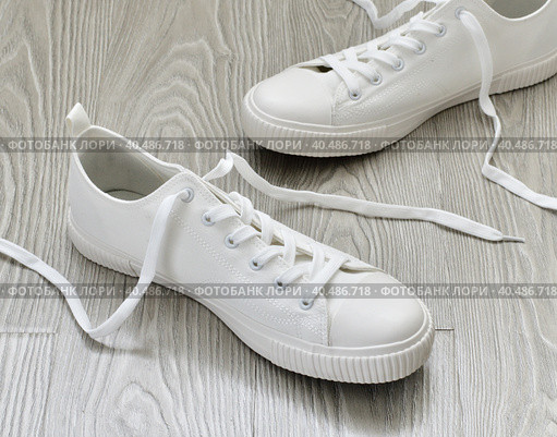 White sneakers with untied laces are on floor. Стоковое фото, фотограф Володина Ольга / Фотобанк Лори