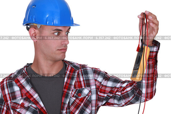 Wide-eyed tradesman staring at a multimeter. Стоковое фото, фотограф Phovoir Images / Фотобанк Лори