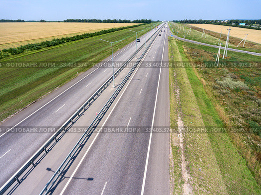 Wide highway with four lanes, aerial view at straight motorway in agricultural fields. Russia. Стоковое фото, фотограф Кекяляйнен Андрей / Фотобанк Лори