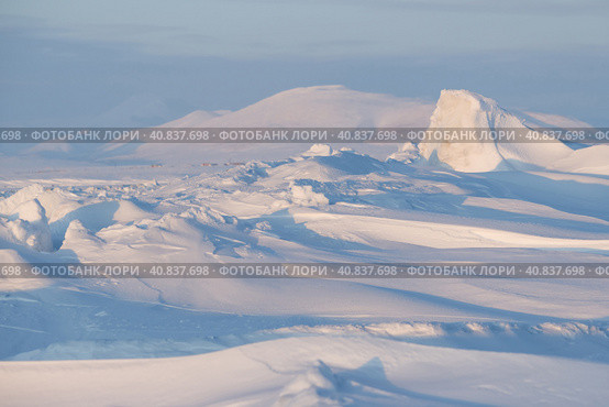 Winter arctic landscape. Ice hummocks on the frozen sea in the Arctic. Cold frosty winter weather. Harsh polar climate. View of snow-covered ice and snow-capped mountains. Amazing nature of the Arctic. Стоковое фото, фотограф Андрей Степанов / Фотобанк Лори
