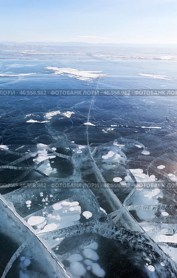 Winter landscape of frozen Baikal Lake in cold winter day. Natural seasonal background with blue ice cover with white bubbles and cracks. Winter travels and outdoors. Стоковое фото, фотограф Виктория Катьянова / Фотобанк Лори