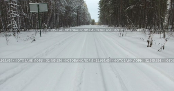Winter road in forest covered with snow, wheel tracks with snowdrifts. Camera moving forward. Стоковое видео, видеограф Кекяляйнен Андрей / Фотобанк Лори