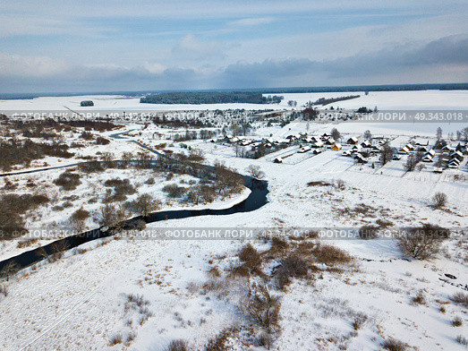 Winter rural landscape. Village and fields covered by snow. Aerial view of small river bends . Стоковое фото, агентство Ingram Publishing / Фотобанк Лори