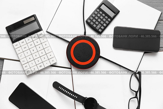 Wireless charger pad, gadgets and calculators on table. Стоковое фото, фотограф Pixel_shot / Фотобанк Лори