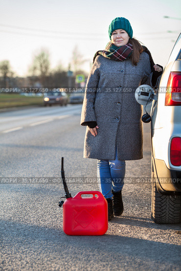 Woman a driver standing on the road leaning her suv with empty plastic can on asphalt, opened car-tank cap, winter season. Стоковое фото, фотограф Кекяляйнен Андрей / Фотобанк Лори