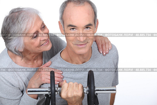 Woman admiring a man lifting a dumbell. Стоковое фото, агентство Ingram Publishing / Фотобанк Лори