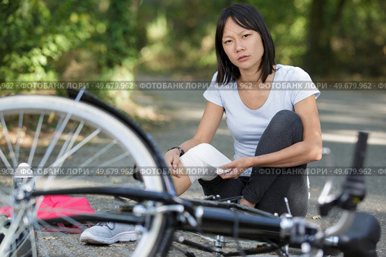woman applying bandage to knee after falling from bicycle. Стоковое фото, агентство Ingram Publishing / Фотобанк Лори