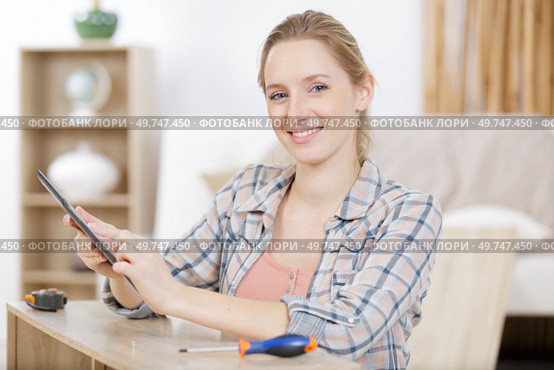 woman assembling furniture looking on tablet for instructions. Стоковое фото, агентство Ingram Publishing / Фотобанк Лори