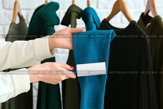 Woman cleaning clothes with lint roller on brick background. Стоковое фото, фотограф Pixel_shot / Фотобанк Лори
