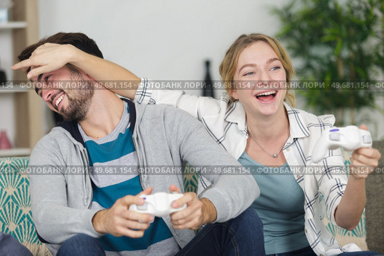 woman closing mans eyes while playing video games. Стоковое фото, агентство Ingram Publishing / Фотобанк Лори