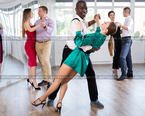 Woman dances incendiary tango with African man partner during choreography lesson. Стоковое фото, фотограф Яков Филимонов / Фотобанк Лори