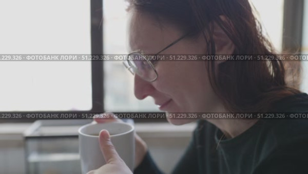 Woman enjoying hot beverage by window. Стоковое видео, видеограф Константин Шишкин / Фотобанк Лори
