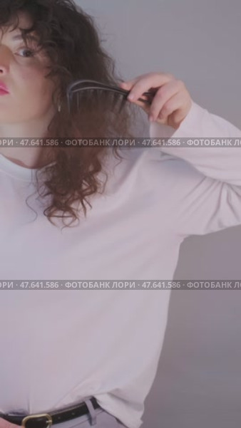 Woman enjoys home hair care: gently brushing curls and stimulating hair growth with a soothing scalp massage. Стоковое видео, видеограф Svetlana Golovco / Фотобанк Лори