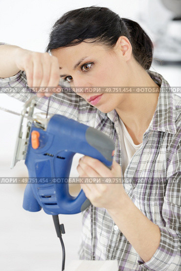 woman fixes a bar on a miter saw in workshop. Стоковое фото, агентство Ingram Publishing / Фотобанк Лори